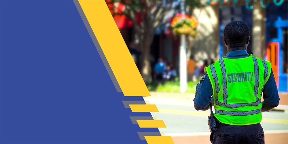 A man with a security vest looking down a street.